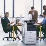 Xerox® VersaLink® C7100 serie, multifunctionele kleurenprinter op de werkplek Team aan het werk in een kantoor met bedrukte papieren en de multifunctionele kleurenprinter Xerox® VersaLink® C7100 serie