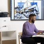 Hommes travaillant sur un ordinateur portable devant une Imprimante couleur multifonctions Xerox® VersaLink® C415