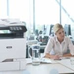 Xerox® VersaLink® C625 multifunctionele kleurenprinter op de werkplek Twee vrouwen aan het werk in een kantoor naast een Xerox® VersaLink® C625 multifunctionele kleurenprinter