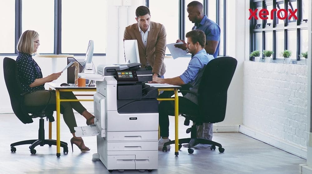 Employés de bureau collaborant à proximité d'une imprimante Xerox.